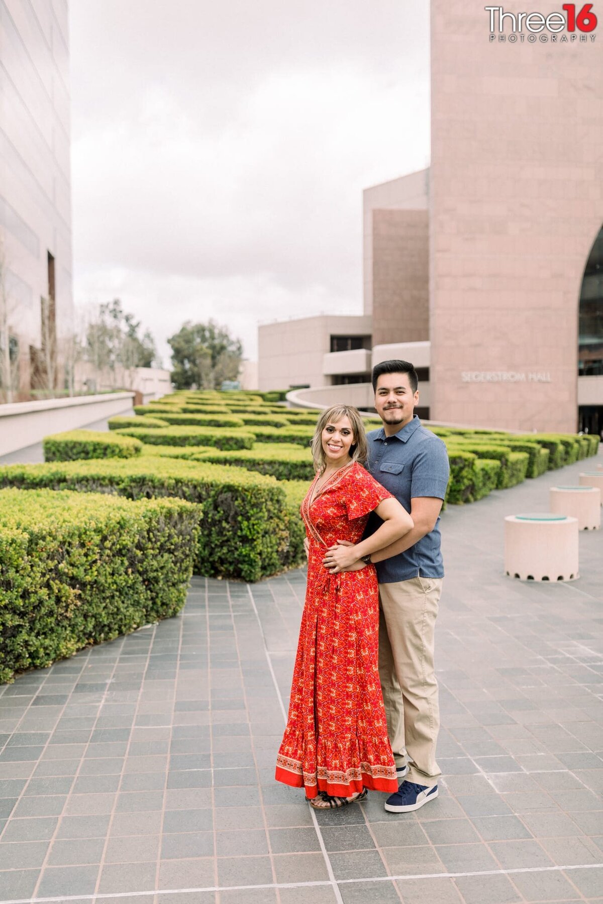 Groom to be holds his Bride from behind as they pose for engagement photos