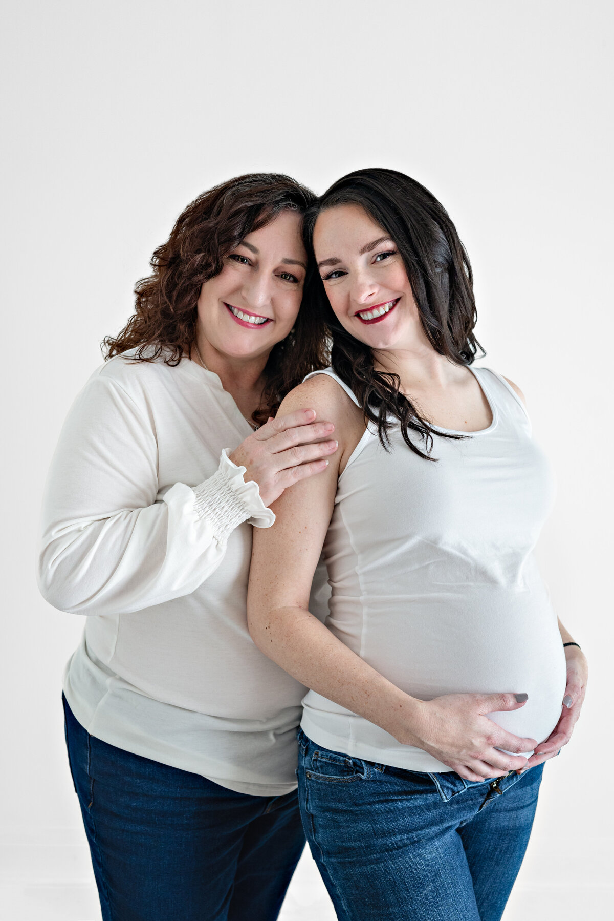 A pregnant woman and her mother pose together in a studio in Huntsville Alabama