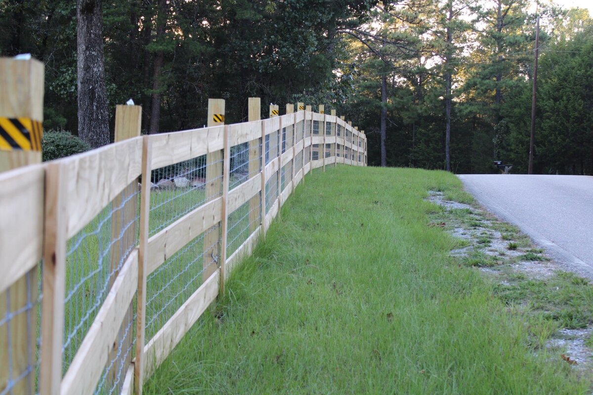 wooden-and-wire-fence-between-road-and-treeline