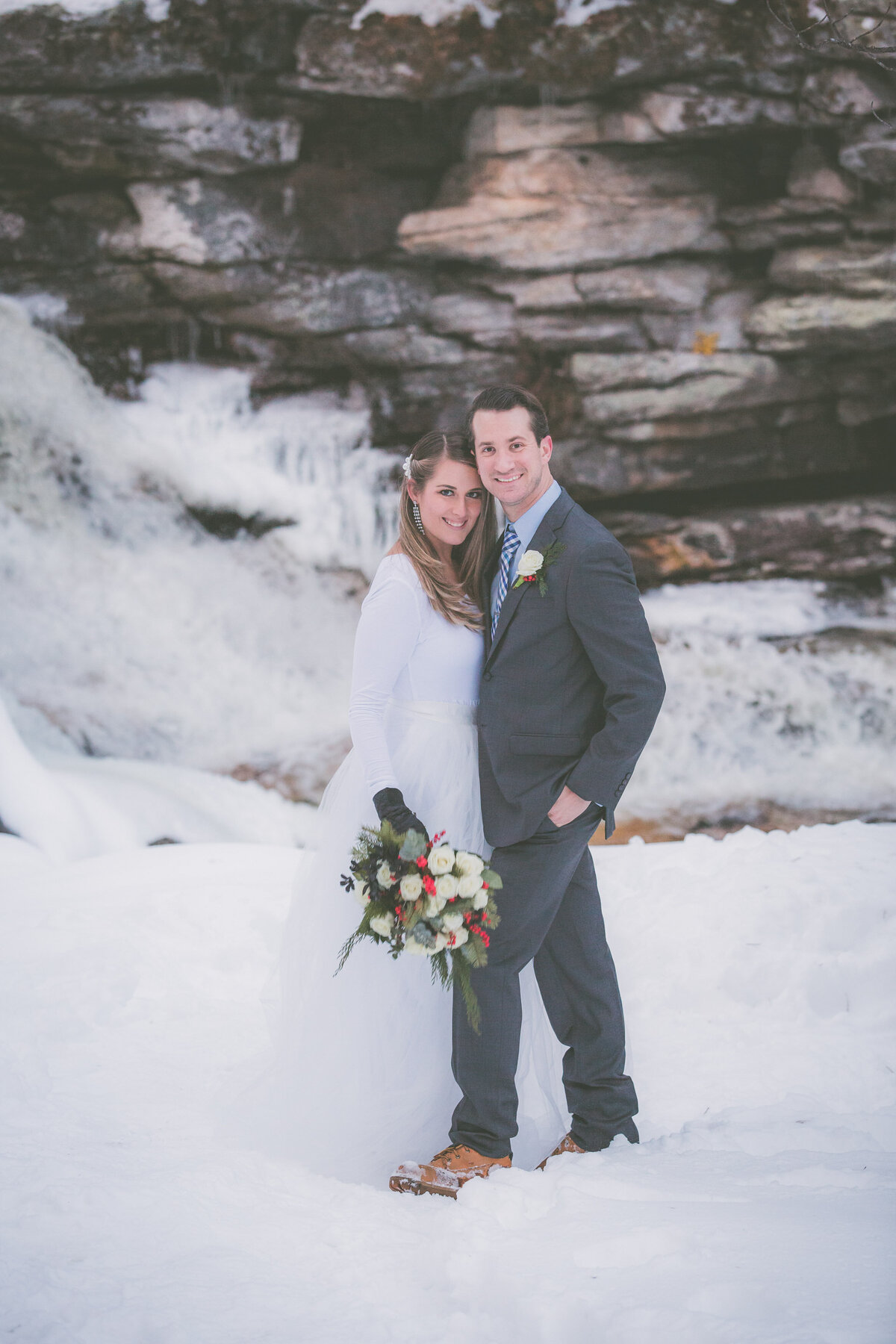Groom puts hand in pocket and poses with wife during winter adventure elopement.