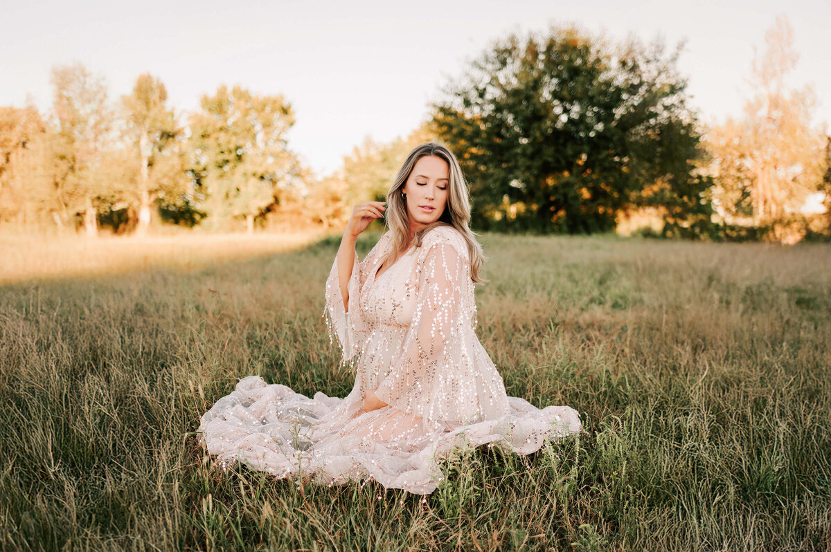 Springfield Mo maternity photographer Jessica Kennedy of The XO Photogrpahy cpatures mom holding baby bump brushing her hair baby in field at sunset