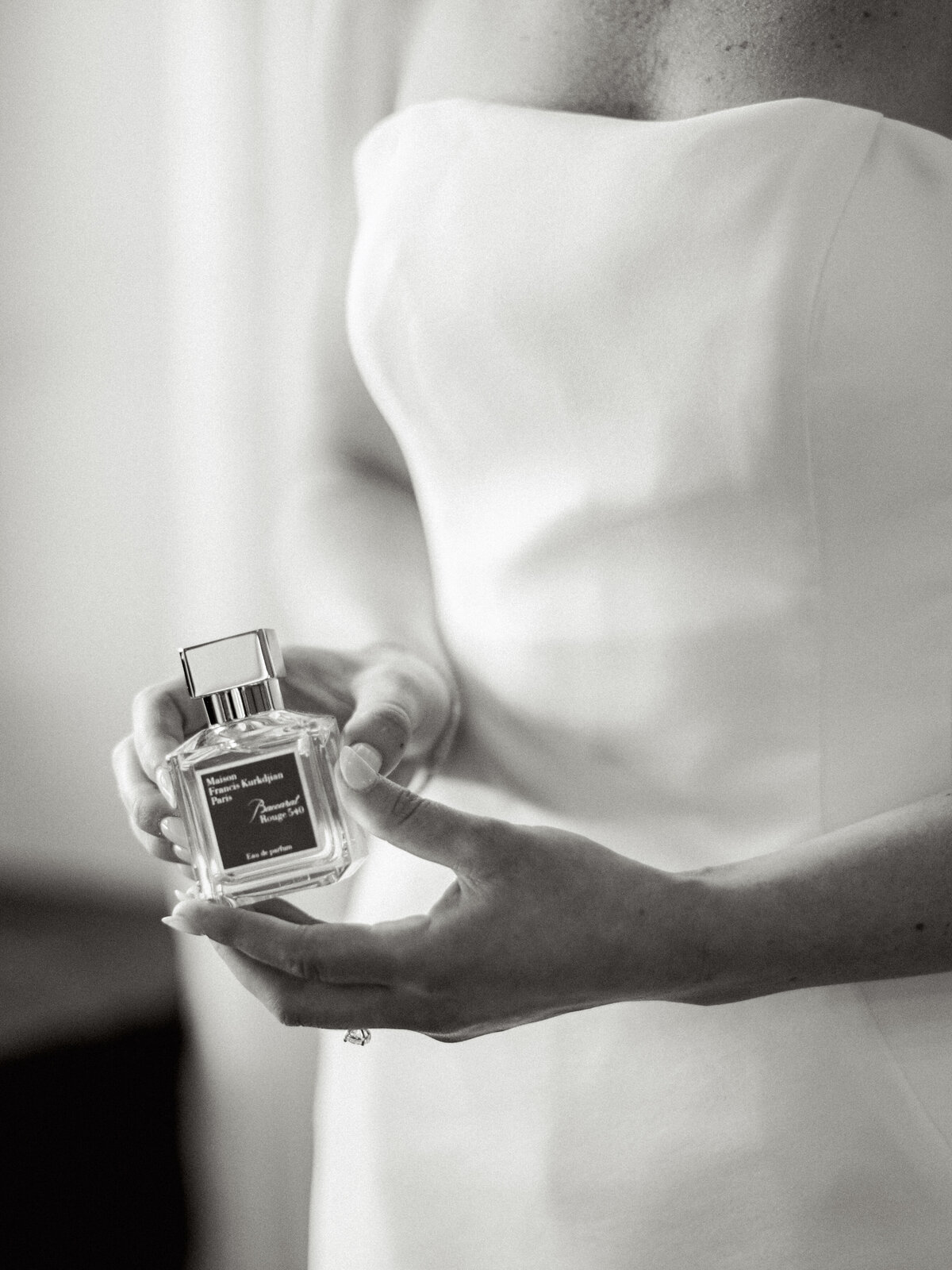Black and white close up photo of bride's hands holding her perfume bottle