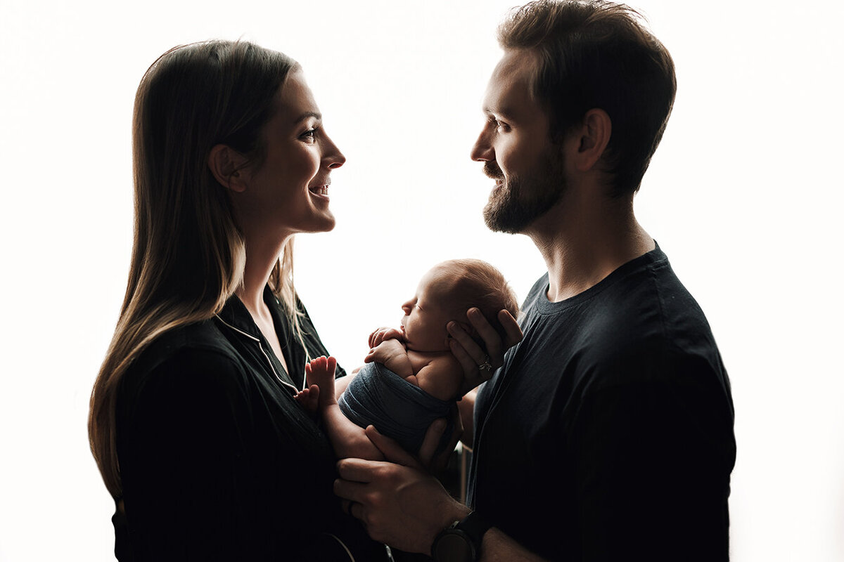Beautiful Fort Collins Colorado family holding their newborn baby girl and smiling at each other