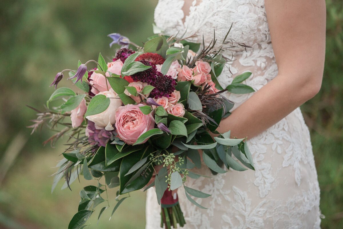 The bouquet held by the bride is made of roses, carnation, and green leaves.  Captured by Stephanie Eddy, Colorado wedding photographer