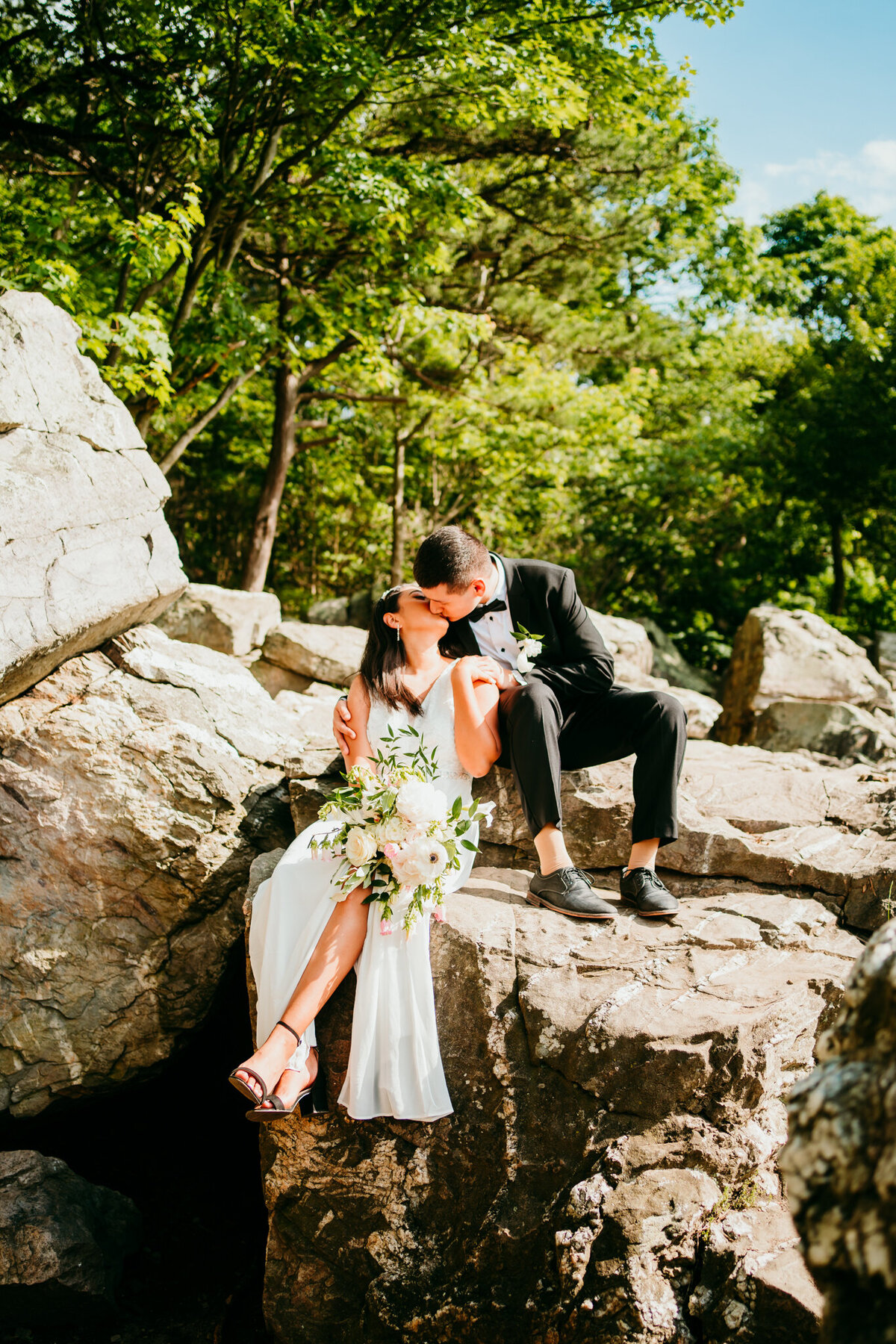 Bride and groom sharing an intimate moment on sunlit boulders elopement