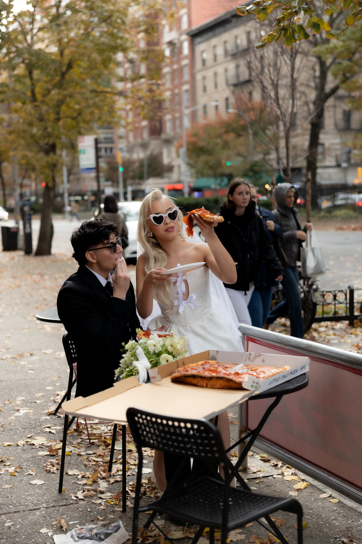 Bride and groom toasting their pizza slices together in celebration of their NYC elopement.