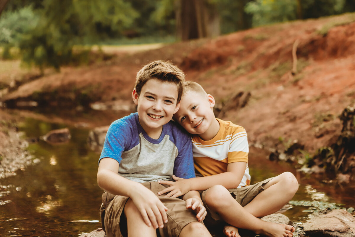 brothers, children sitting in creek