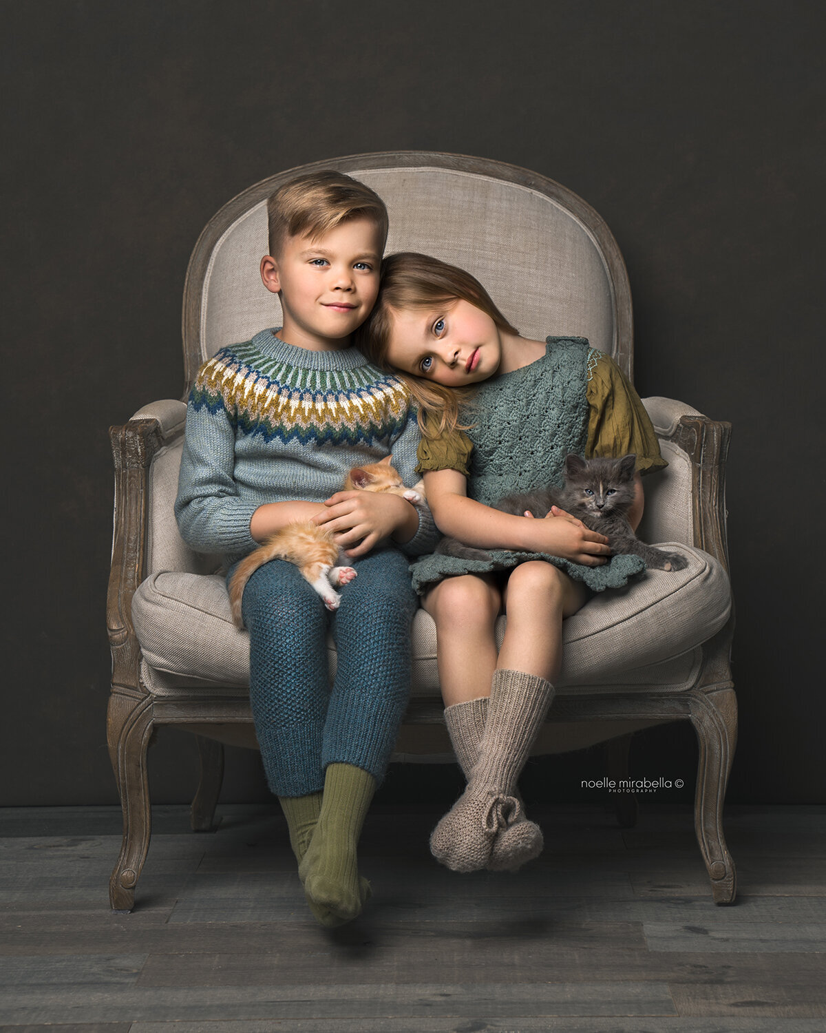 Children posed on vintage chair in a studio portrait