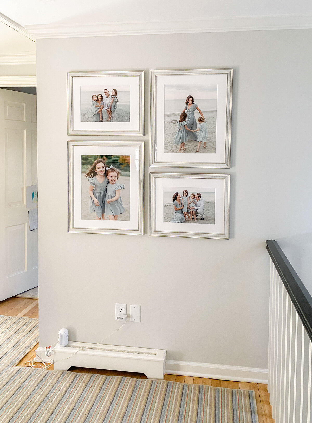 Gallery wall of framed family portraits hang at the top of a flight of stairs