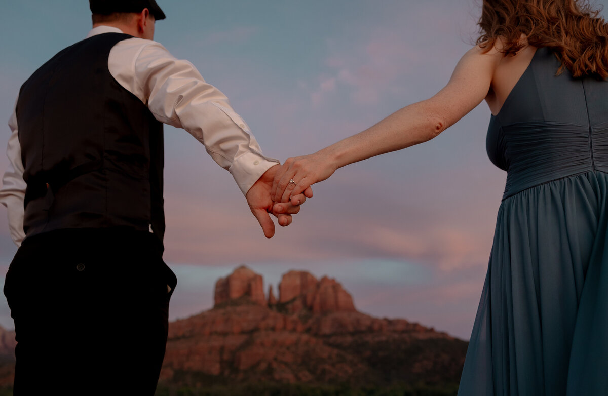 Couple standing against red rock backdrop during Sedona engagement session