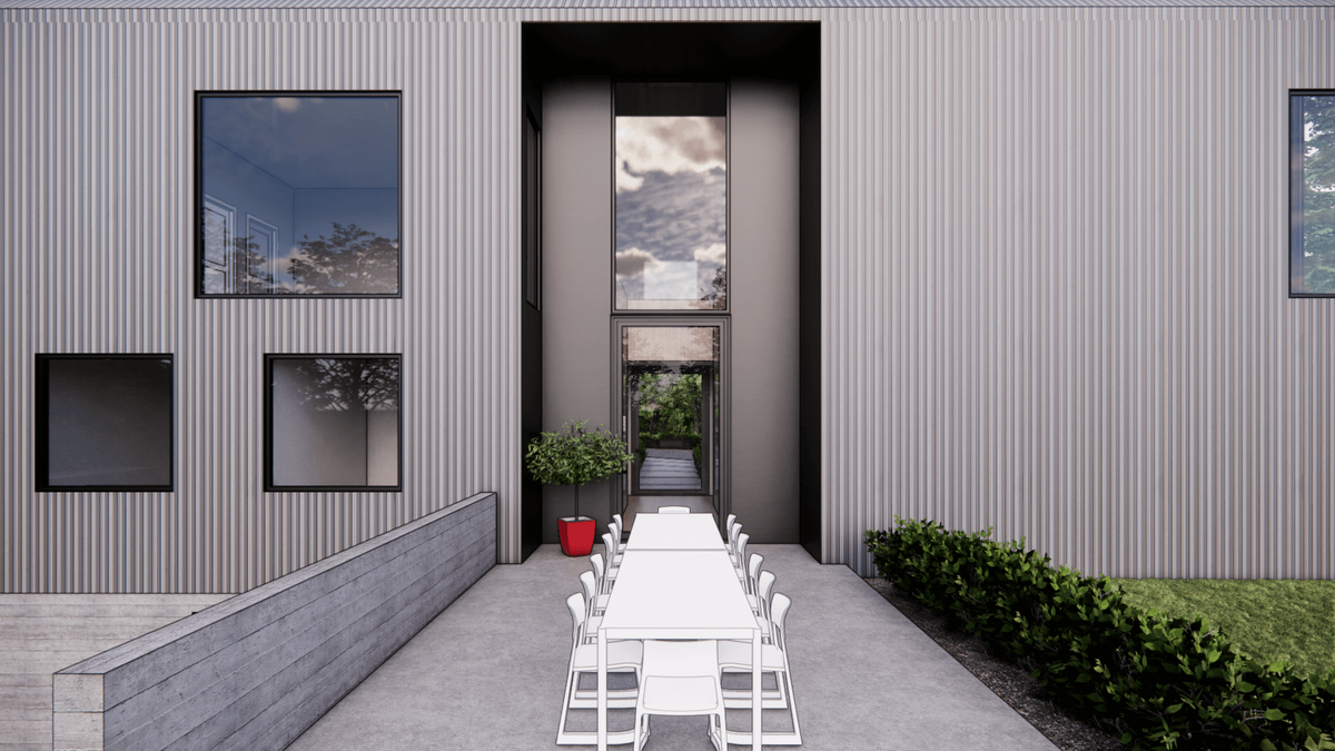 Modern exterior featuring vertical metal siding and large windows. A white outdoor dining set is arranged in the foreground on a concrete patio, flanked by green bushes. A red planter with a tree stands to the left of the entrance.
