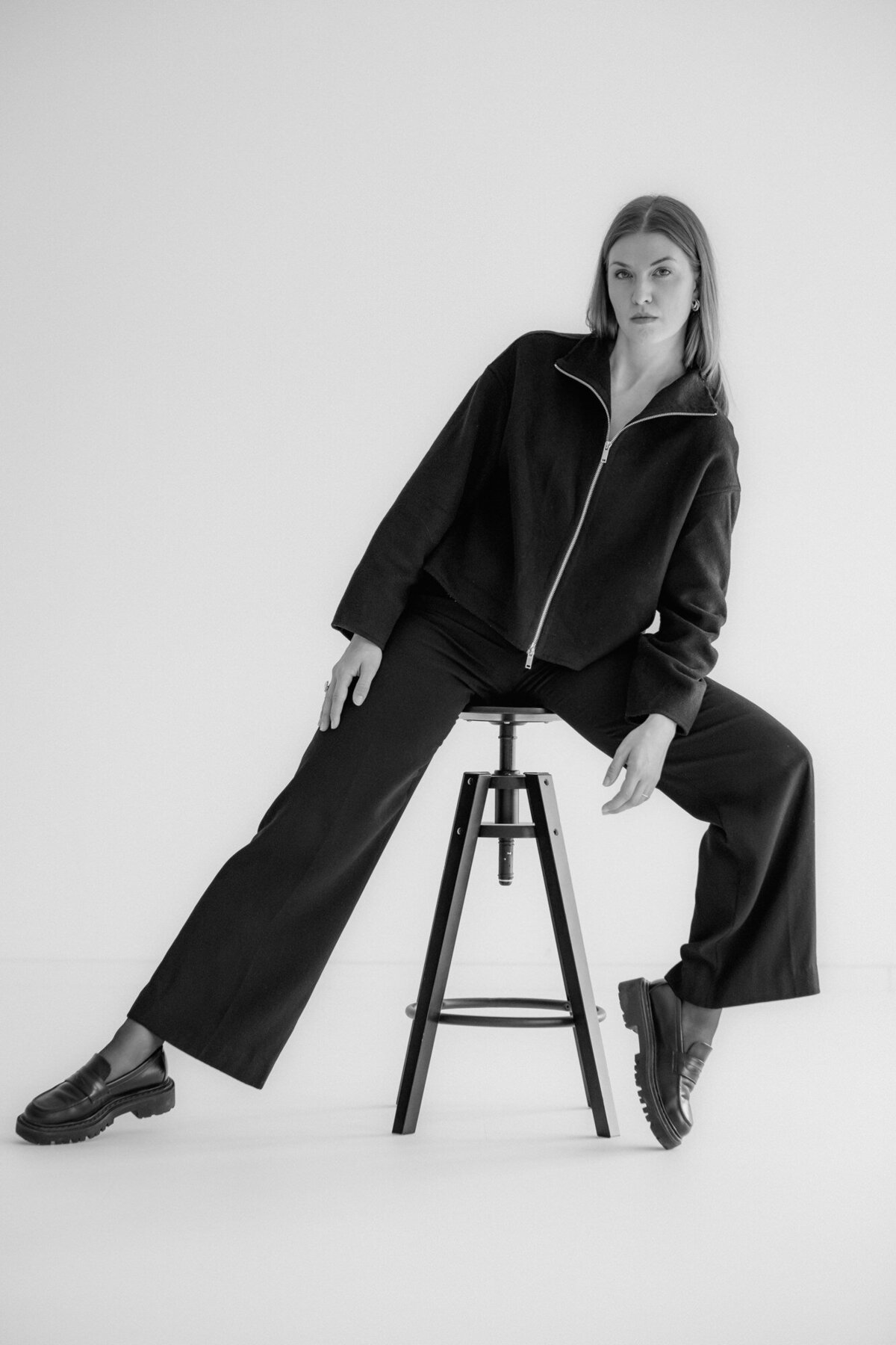 Woman sits in a strong pose on a stool.