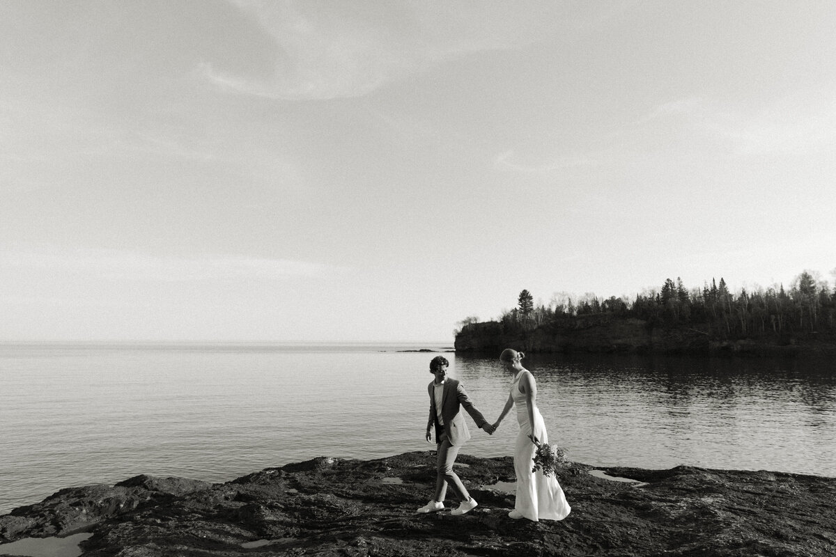 Newlyweds in wedding attire stroll along the Minnesota's North Shore after their wedding ceremony.