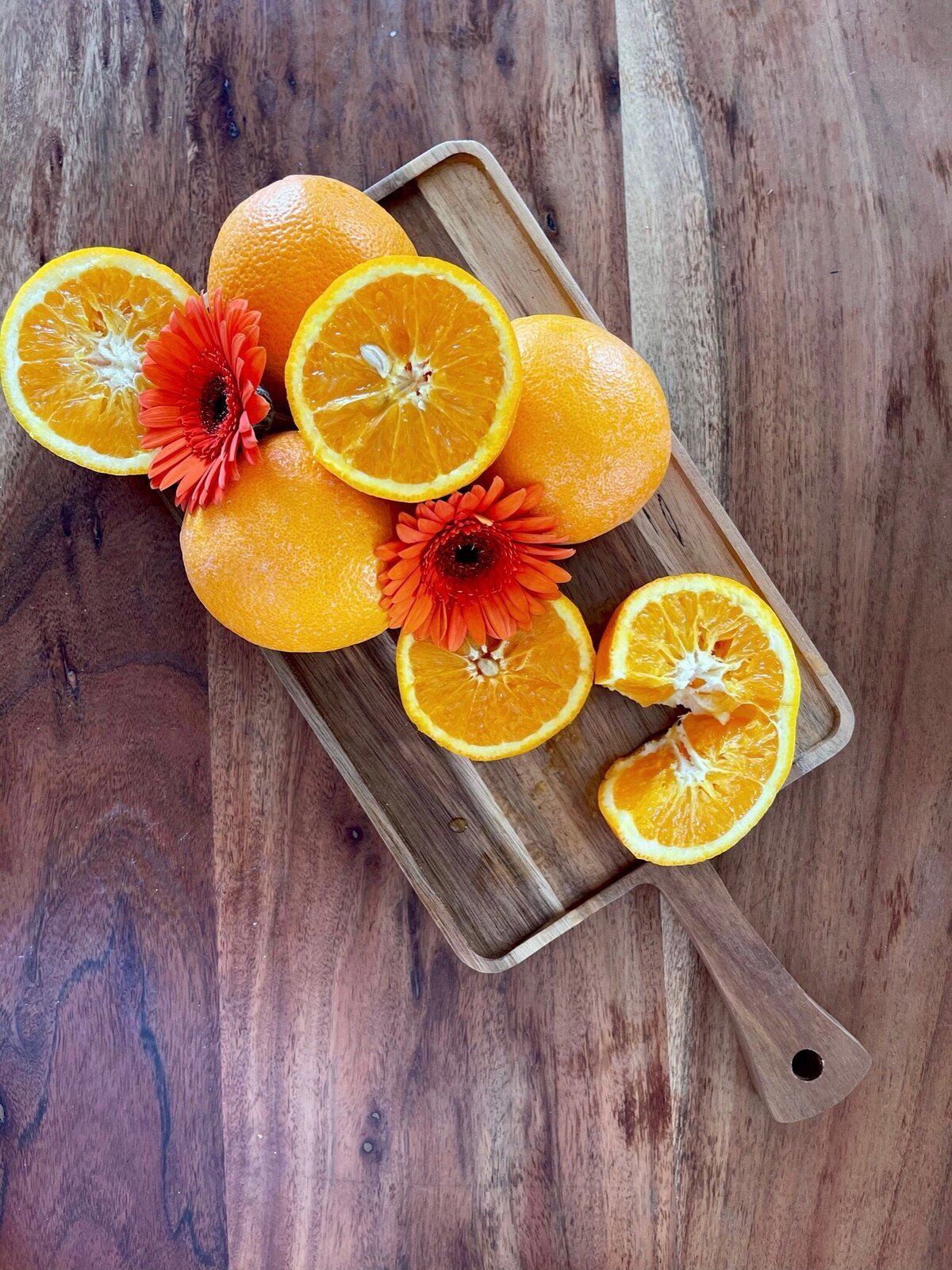 oranges and flowers on a wooden board