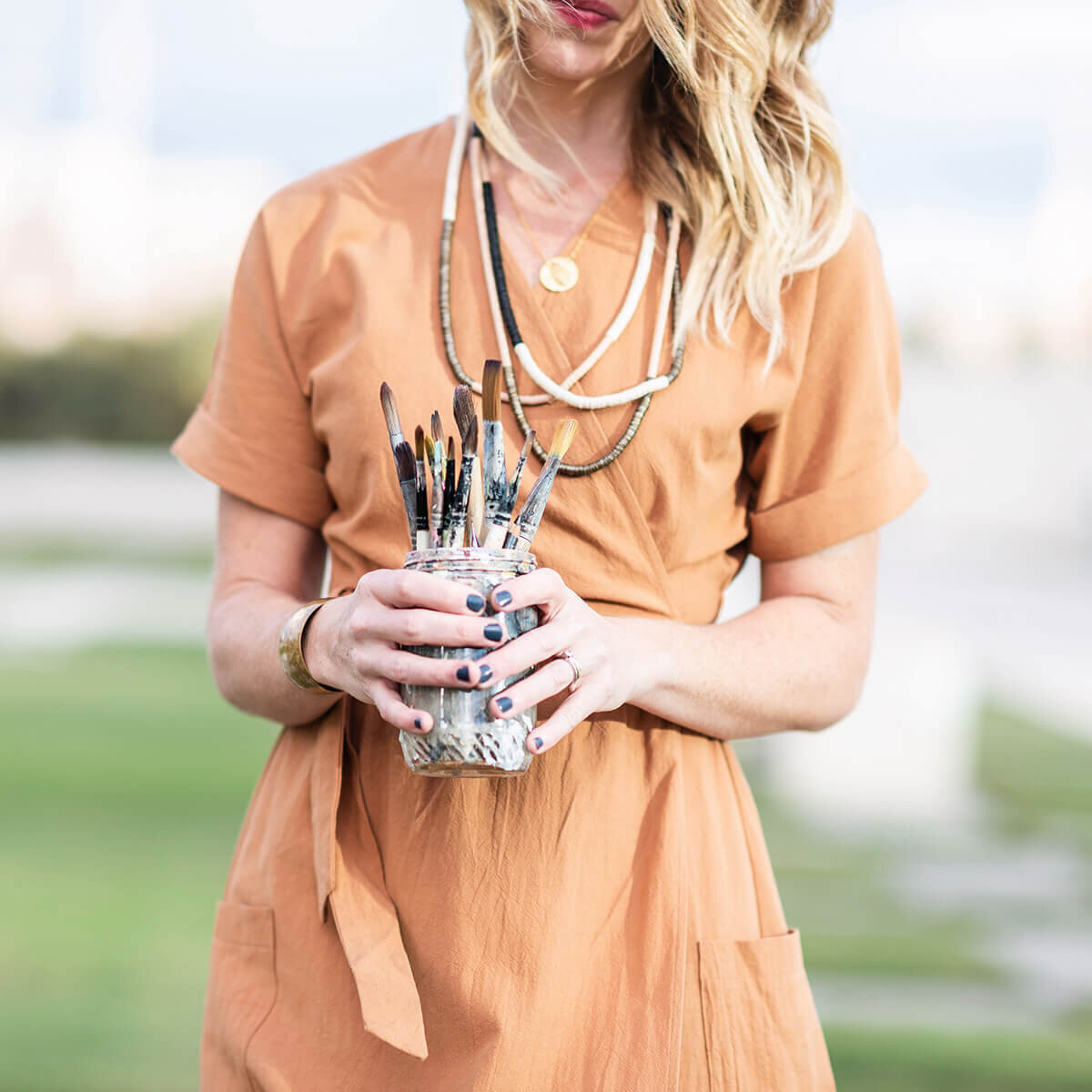 girl holding jar with paintbrushes