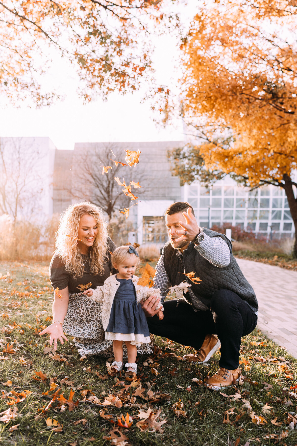 family of three throws fall leaves together