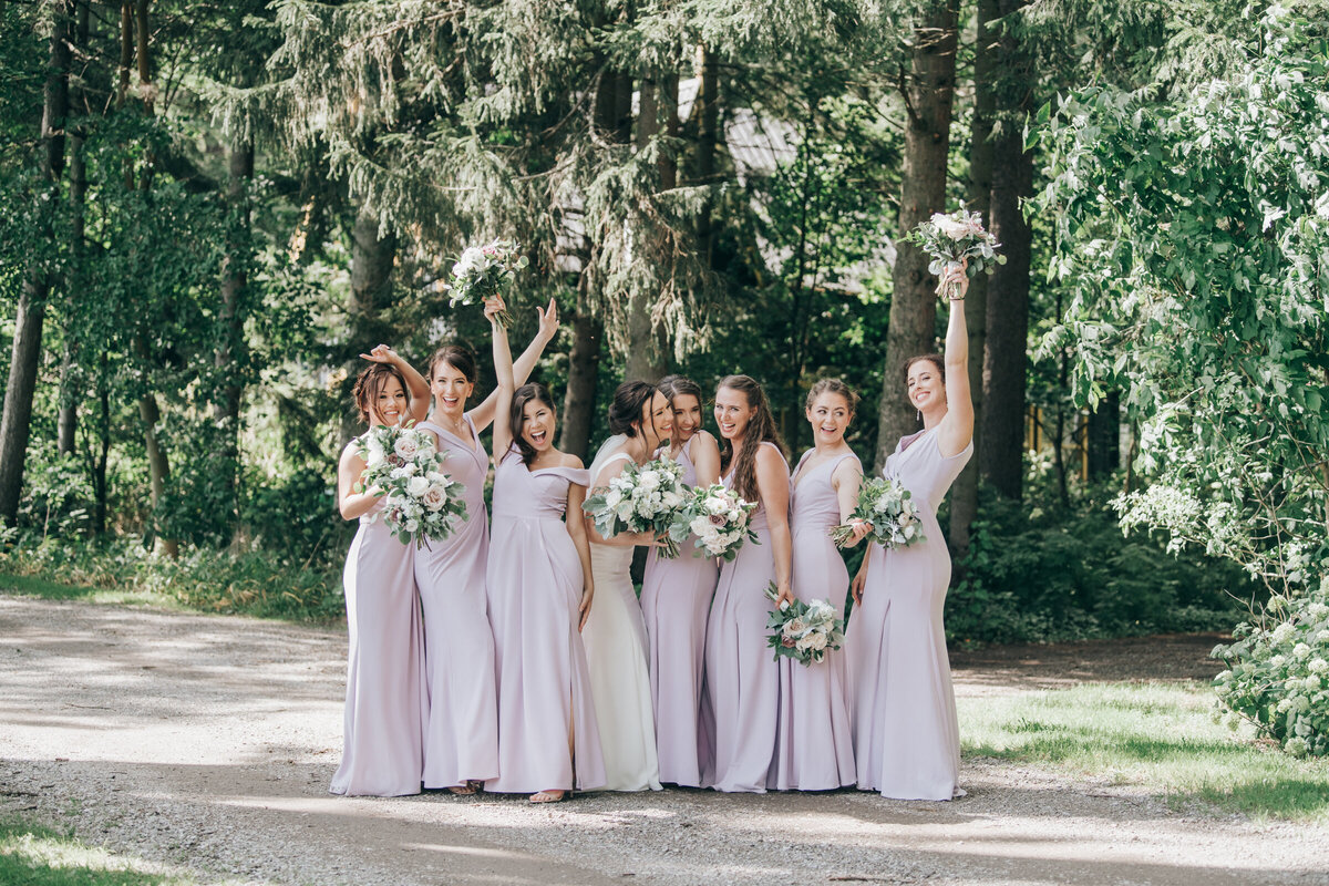 Elegant bridesmaids wearing lavender dresses while posing for photos in an enchanted forest