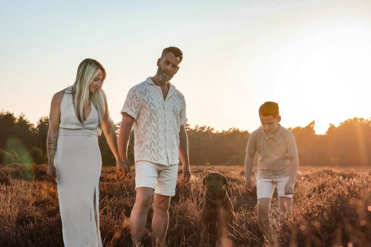 Een liefdevol gezin geniet samen van de 'golden hour' in de natuur, met hun hond aan hun zijde