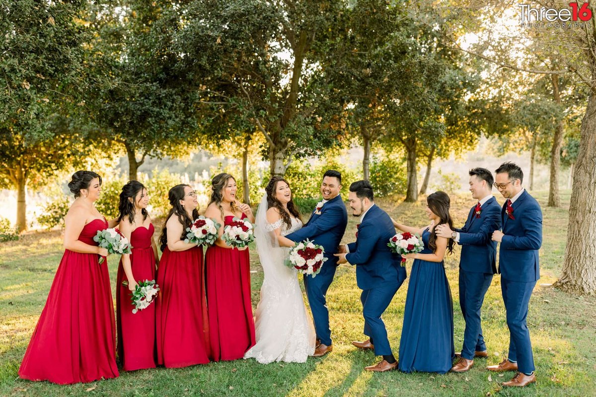 Best man pinches Groom's backend as the bridal party shares in a laugh