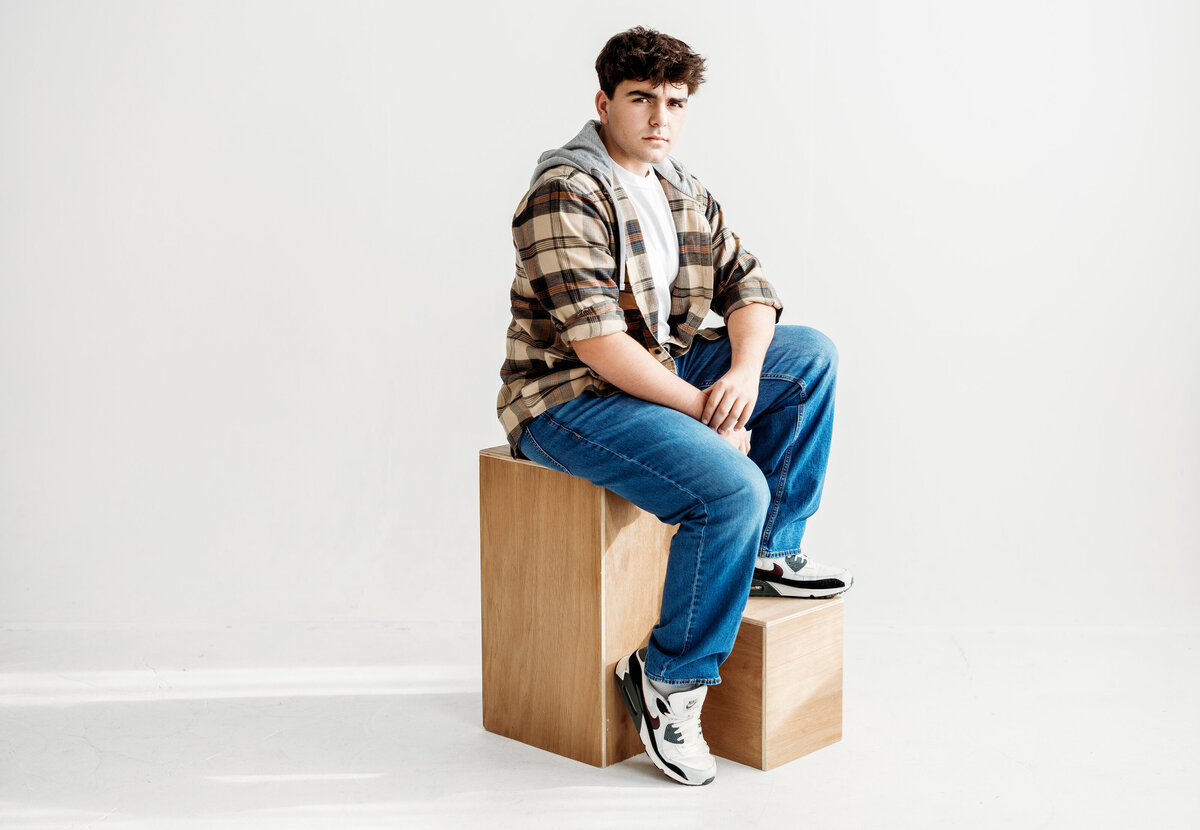 teenage boy poses for a photo in a Denver photo studio on two wooden blocks