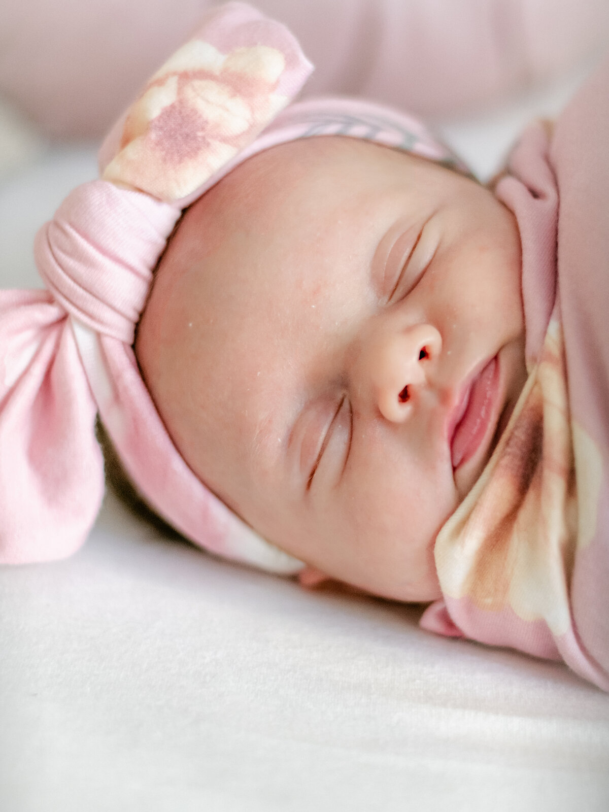 Beautiful newborn  baby girl wearing pink bow asleep in her crib.