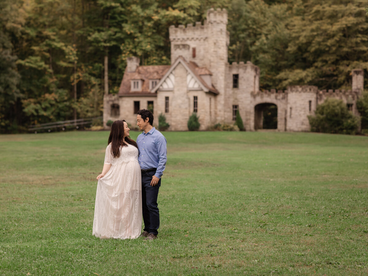 husband and pregnant mother in white lace gown posed for maternity portraits 