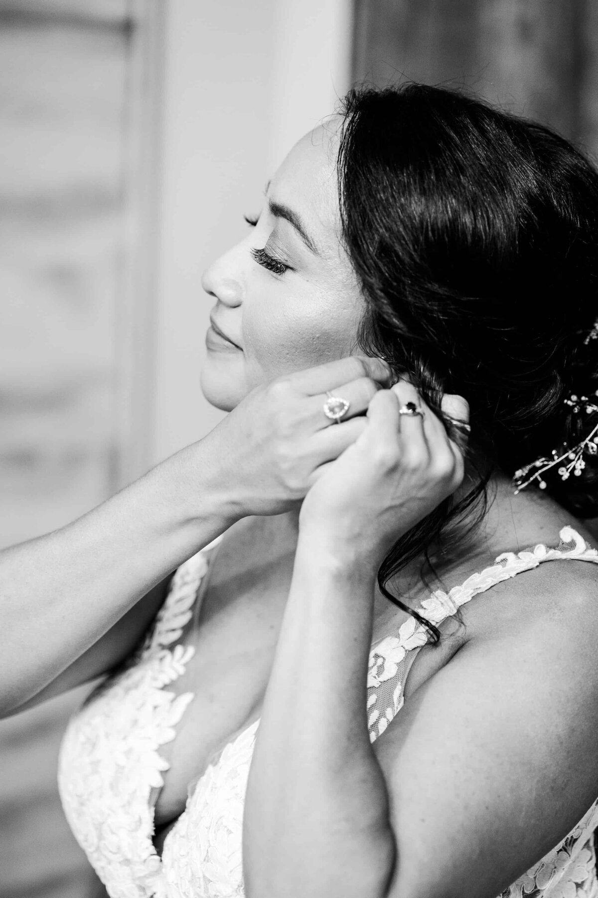 Bride, putting on her earrings in anticipation of the wedding ceremony