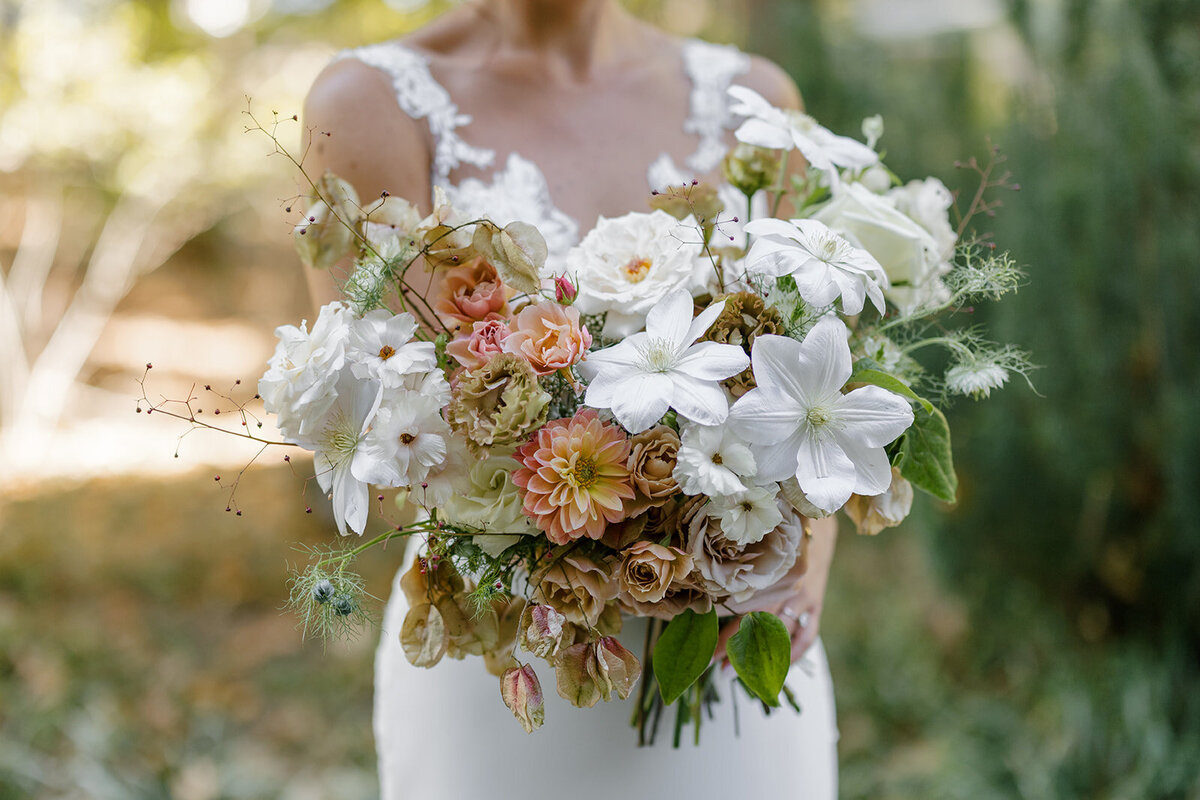 Fall bridal bouquet with lush autumnal colors of mauve, dusty pink, cream, white, peach, taupe, and green. Florals of dahlias, roses, clematis, lisianthus, and natural greenery. Fall wedding in Raleigh, NC. Design by Rosemary and Finch Floral Design in Nashville, TN.