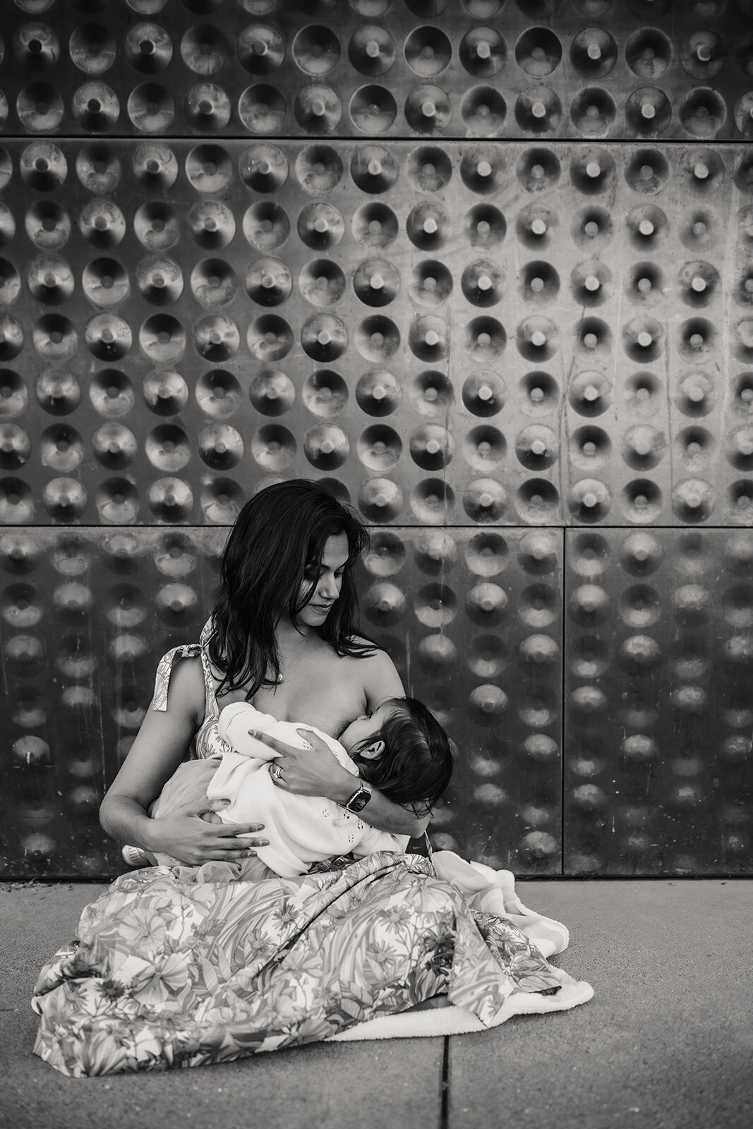 Breastfeeding mother and child in front of de young museum wall in San Francisco