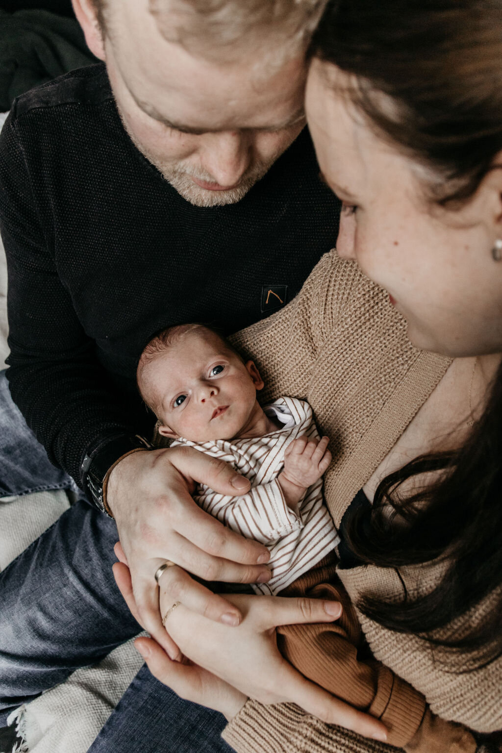 Ouders knuffelen newborn baby tijdens de newbornshoot in Noord-Nederland