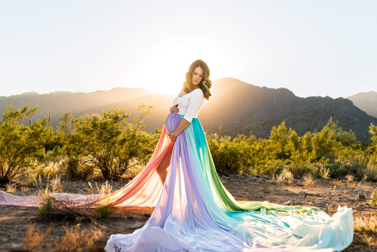 incredible rainbow-baby maternity portrait of mother-to-be holding baby bump in Arizona sunset light