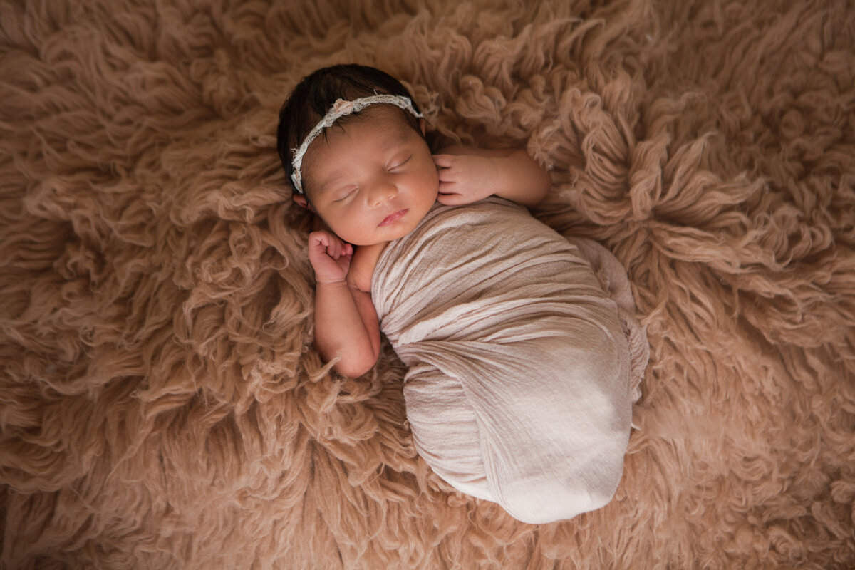 Newborn Baby Girl Wrapped and snuggled with headband
