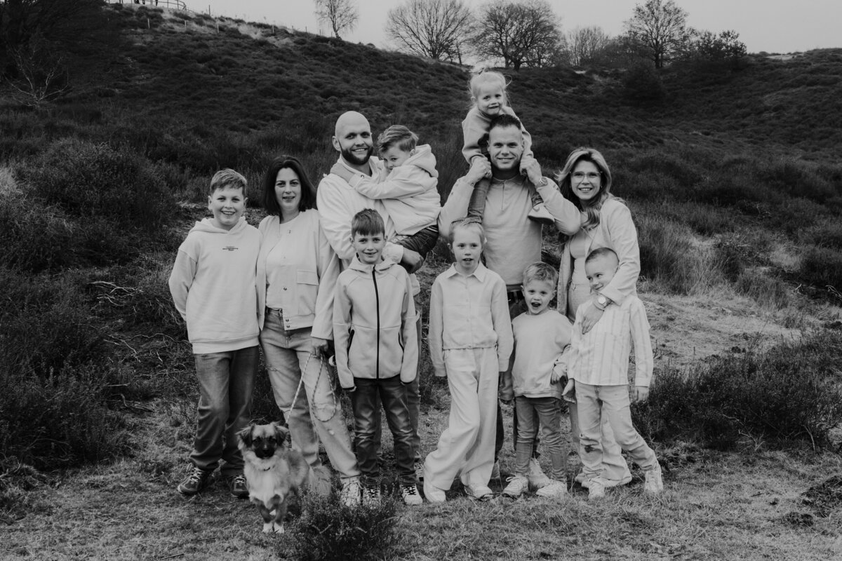  Een zwart-wit afbeelding van een familie in een veld, die samenkomt in een moment van verbondenheid en vreugde.