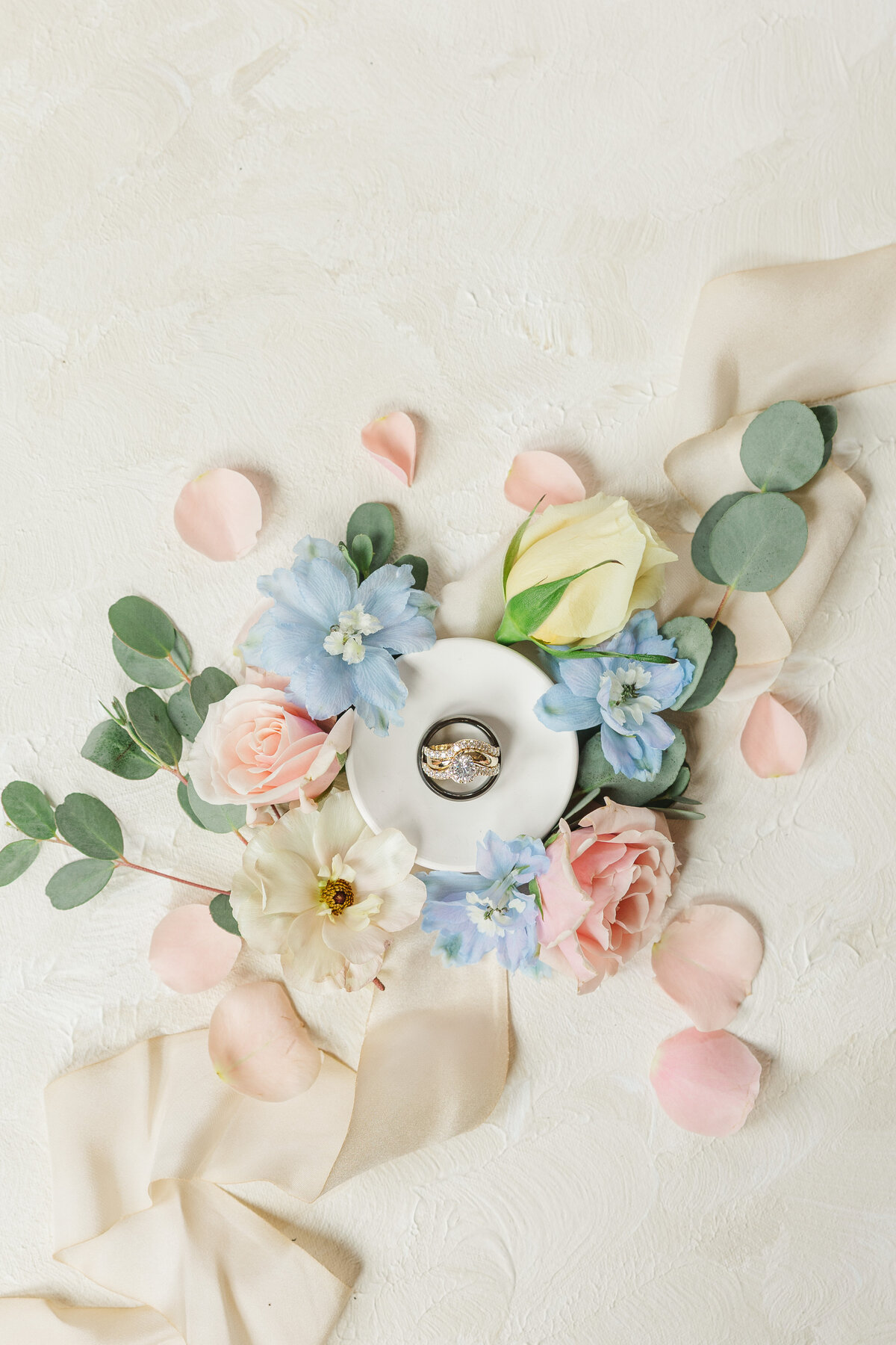 wedding rings, flowers, and other items arranged into a flat lay