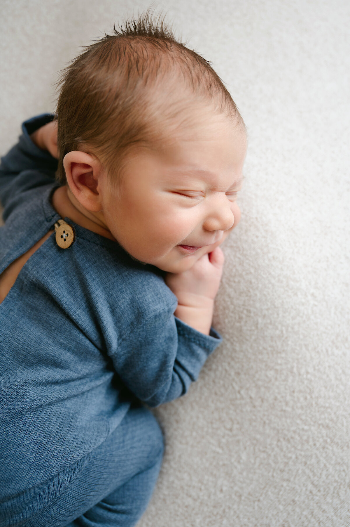 This adorable baby boy’s smile is perfectly captured in our Pittsburgh newborn photography studio. Cozy and cute in a blue onesie, this image will be a keepsake for years to come.