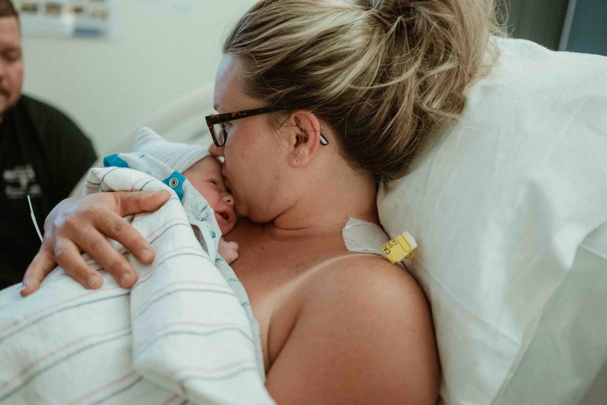 mother kissing her baby's head during skin to skin after a birth in pittsburgh pa