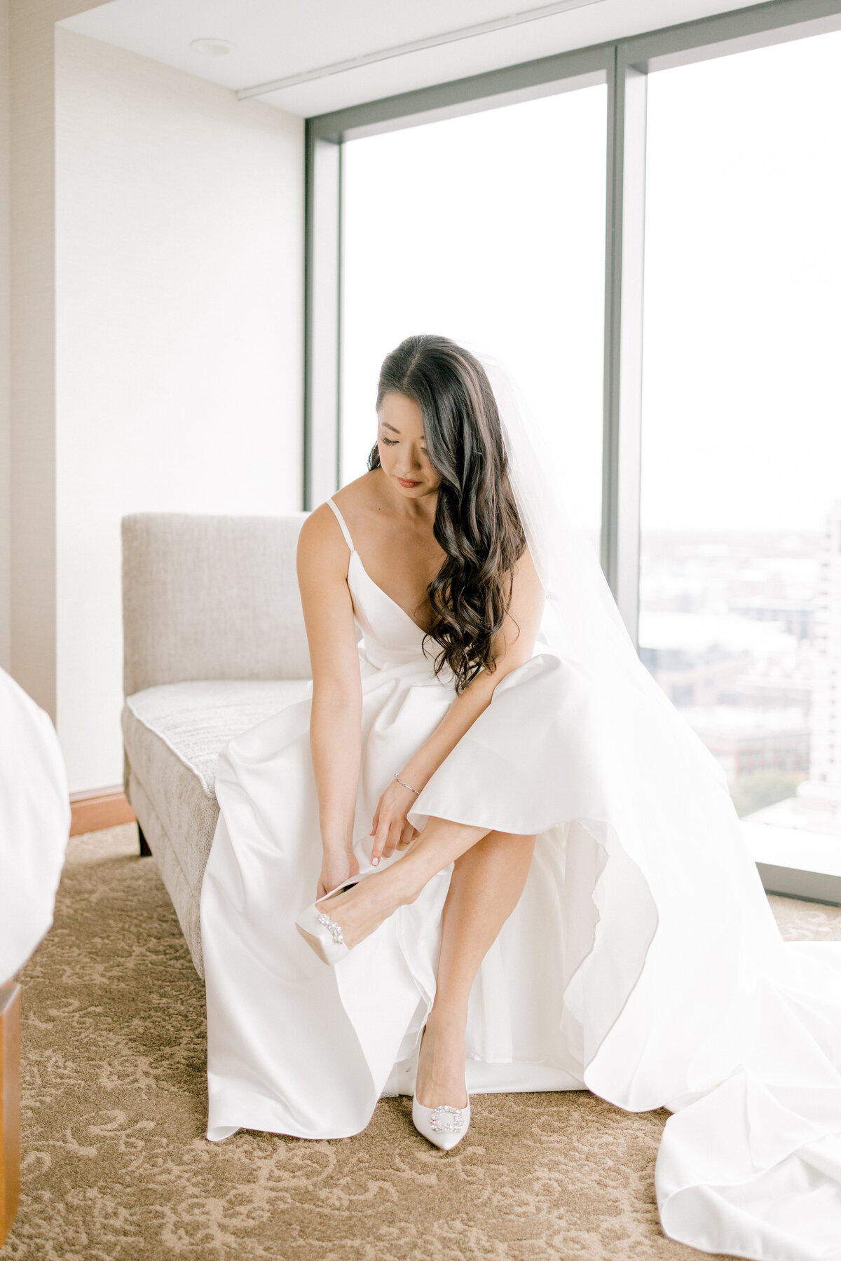 bride sitting on a chaise putting her shoes on