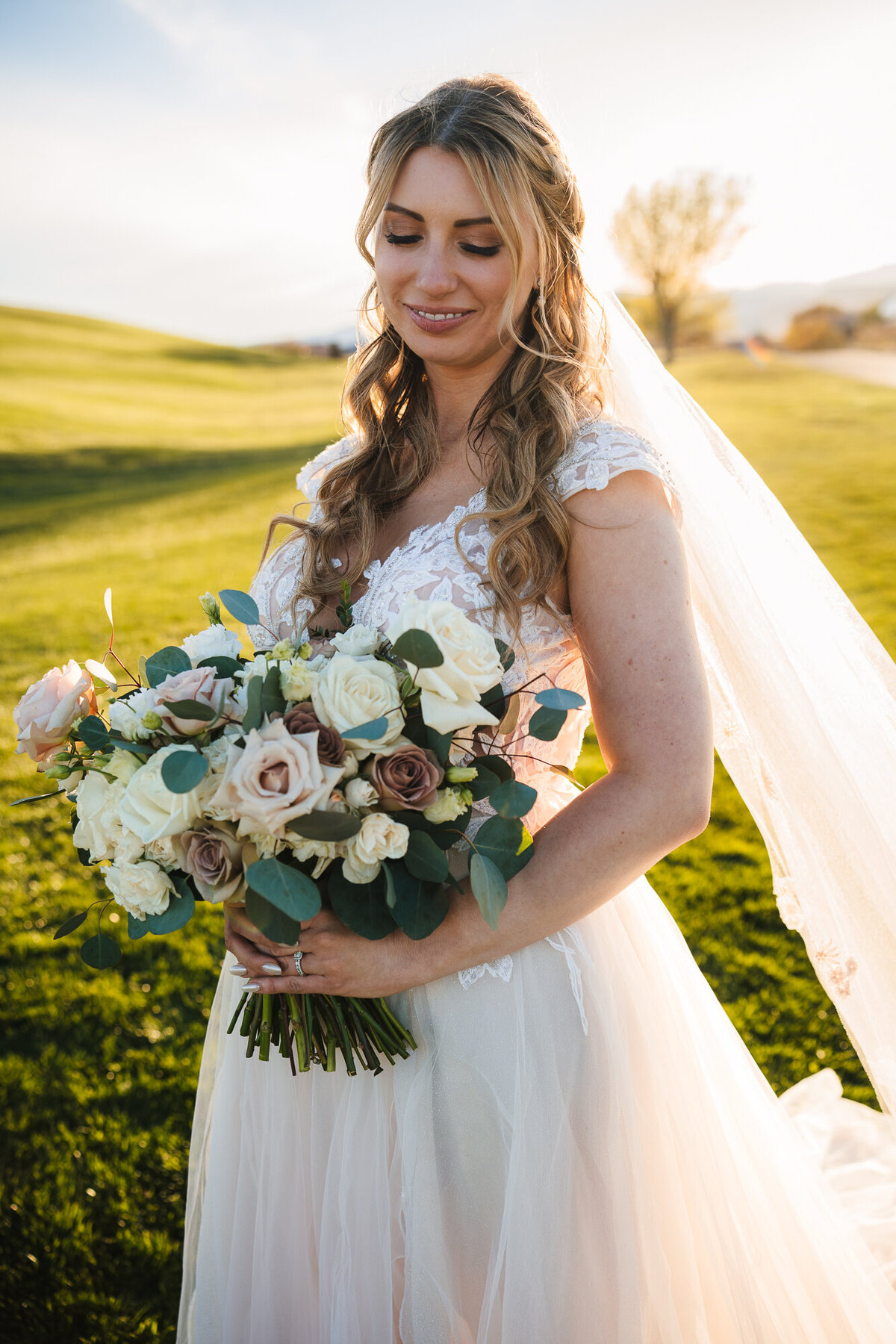 Radiant bride holding her exquisite bouquet of flowers, bathed in the warm glow of a Las Vegas sunset at Revere Golf Club.