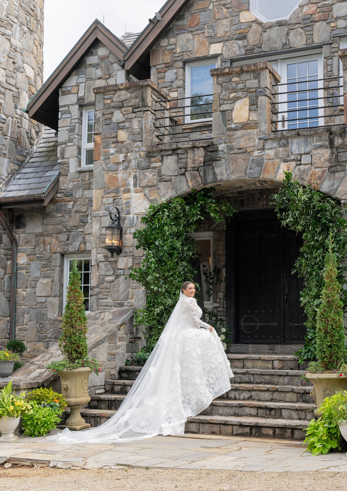 Bride in a long-sleeve lace wedding gown standing on the stone steps of Castle Ladyhawke during a fall wedding in Tuckasegee, North Carolina.