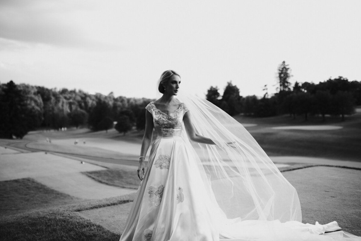 Black and white photo of the bride standing in the middle of a golf course. Image by Jenny Fu Studio
