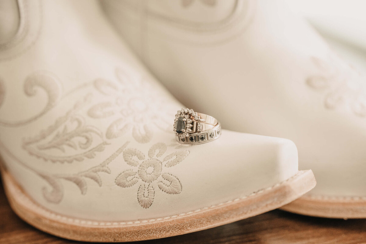 A wedding ring resting on a pair of rustic cowboy boots, symbolizing love and country charm. - photo by Jamie Simmons