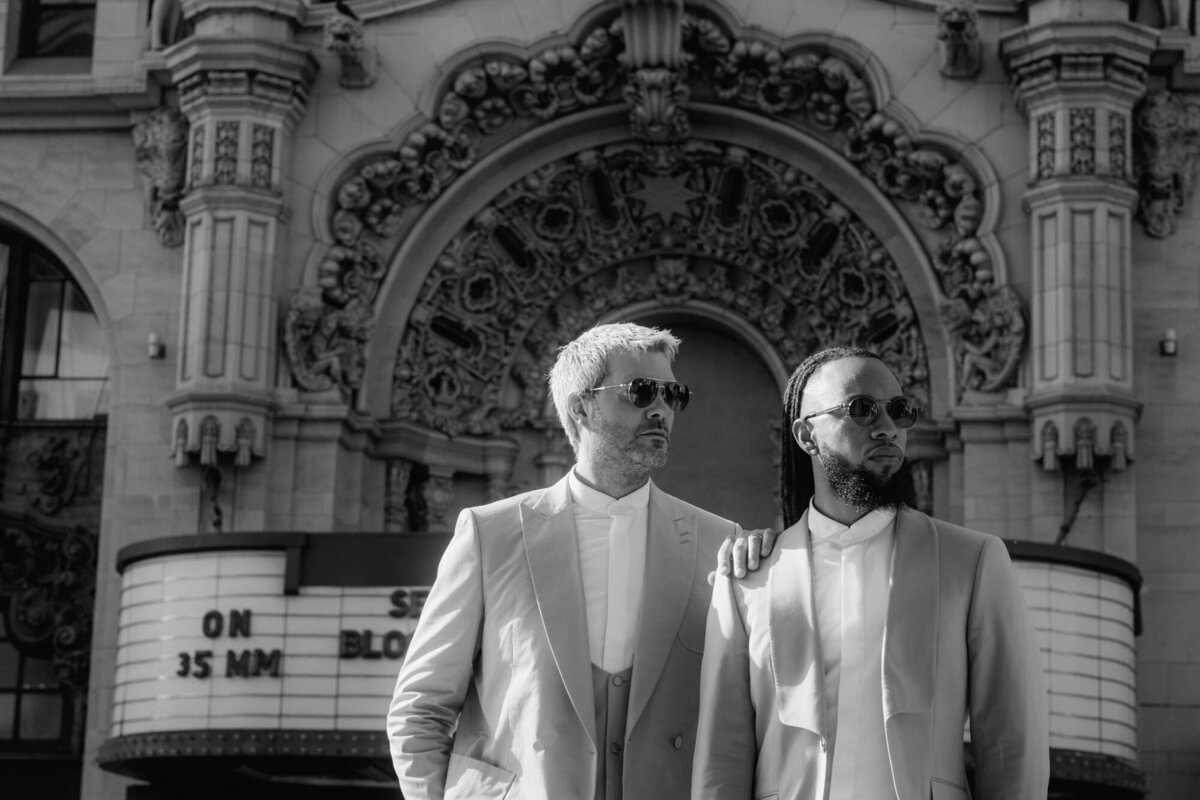 Black an white outdoor couple photography with sunglasses in front of a historical cinema in L.A..