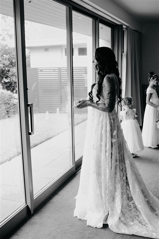 Experience the serene moment as Tamara stands at the window, moments before her wedding ceremony. Embrace the anticipation, joy, and beauty in this heartfelt scene captured in stunning detail.