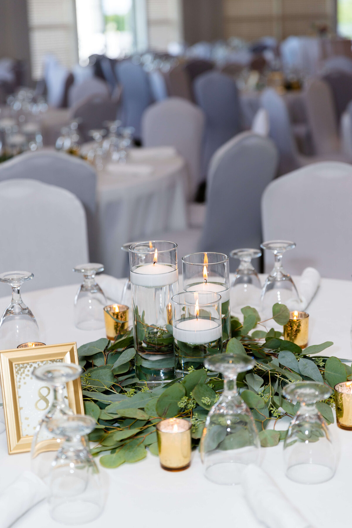 Wedding table centerpiece with candles, glasses and greeenery