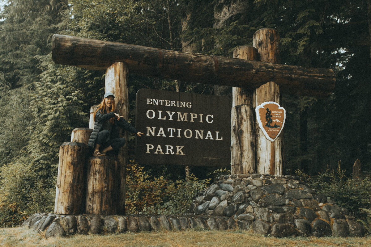 women sitting in front of olympic national park sign