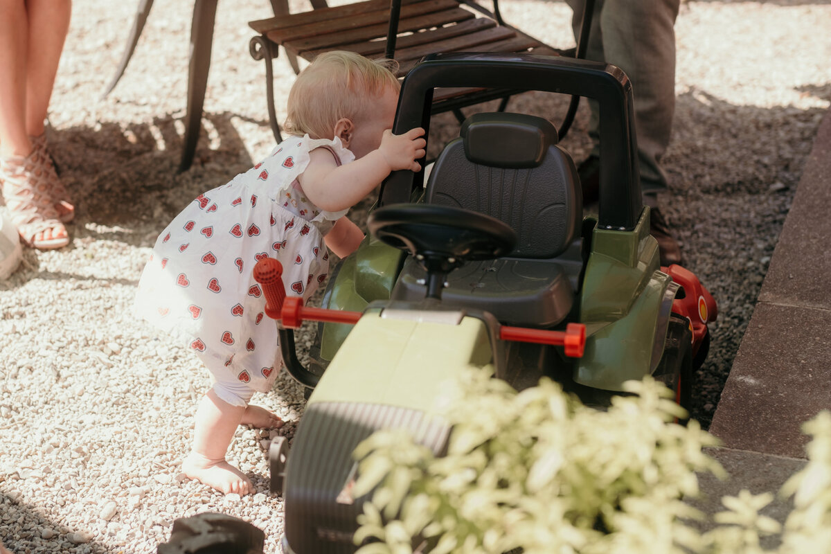 Ein kleines Mädchen spielt mit einem grünen Spielzeugtraktor.