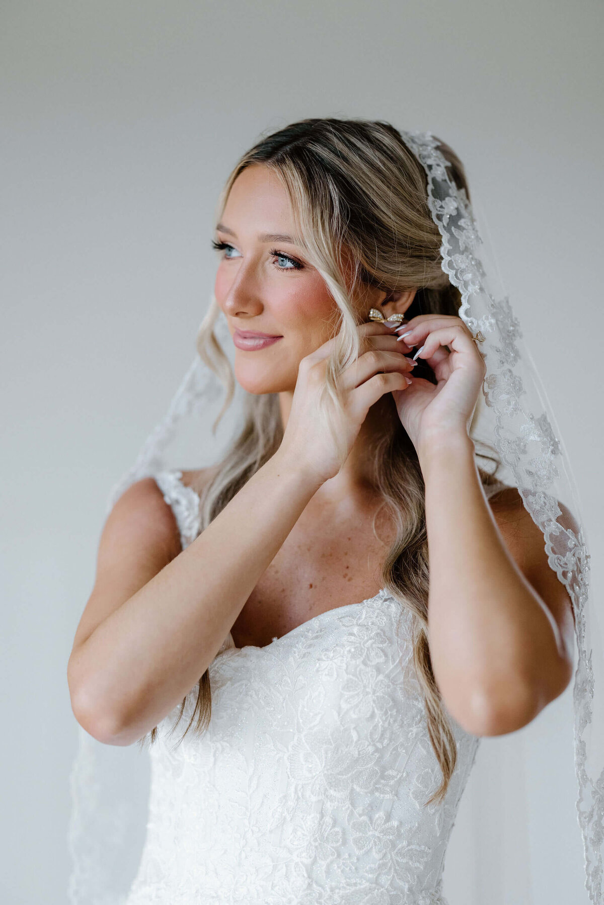 bride putting on diamond studded bow shaped earrings
