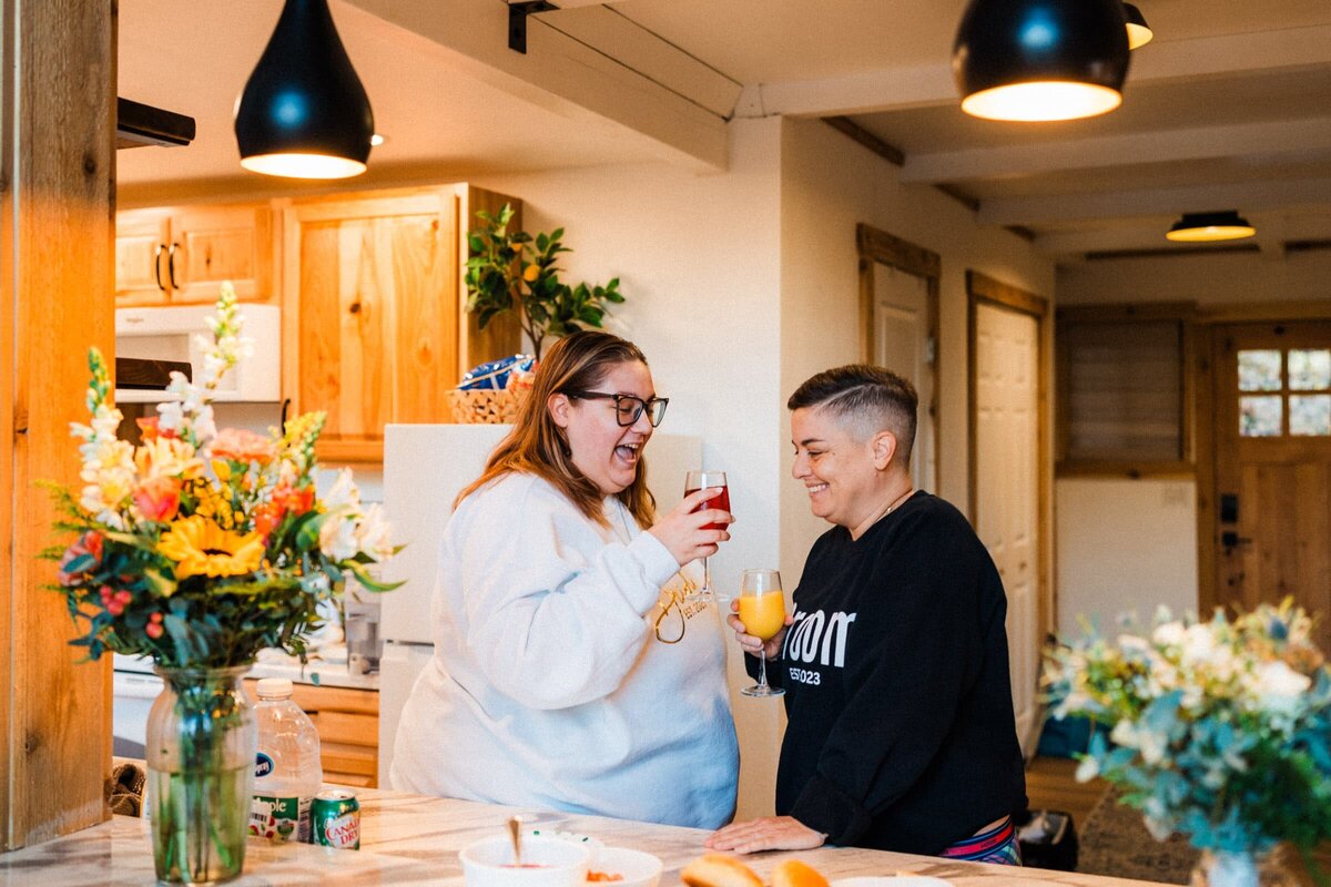 An LGBTQ Washington elopement featuring a couple toasting to their elopement in bride and groom sweatshirts.