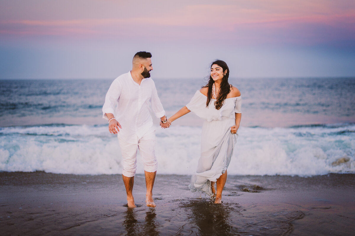 A couple running away from the shore and laughing at bradley beach in nj