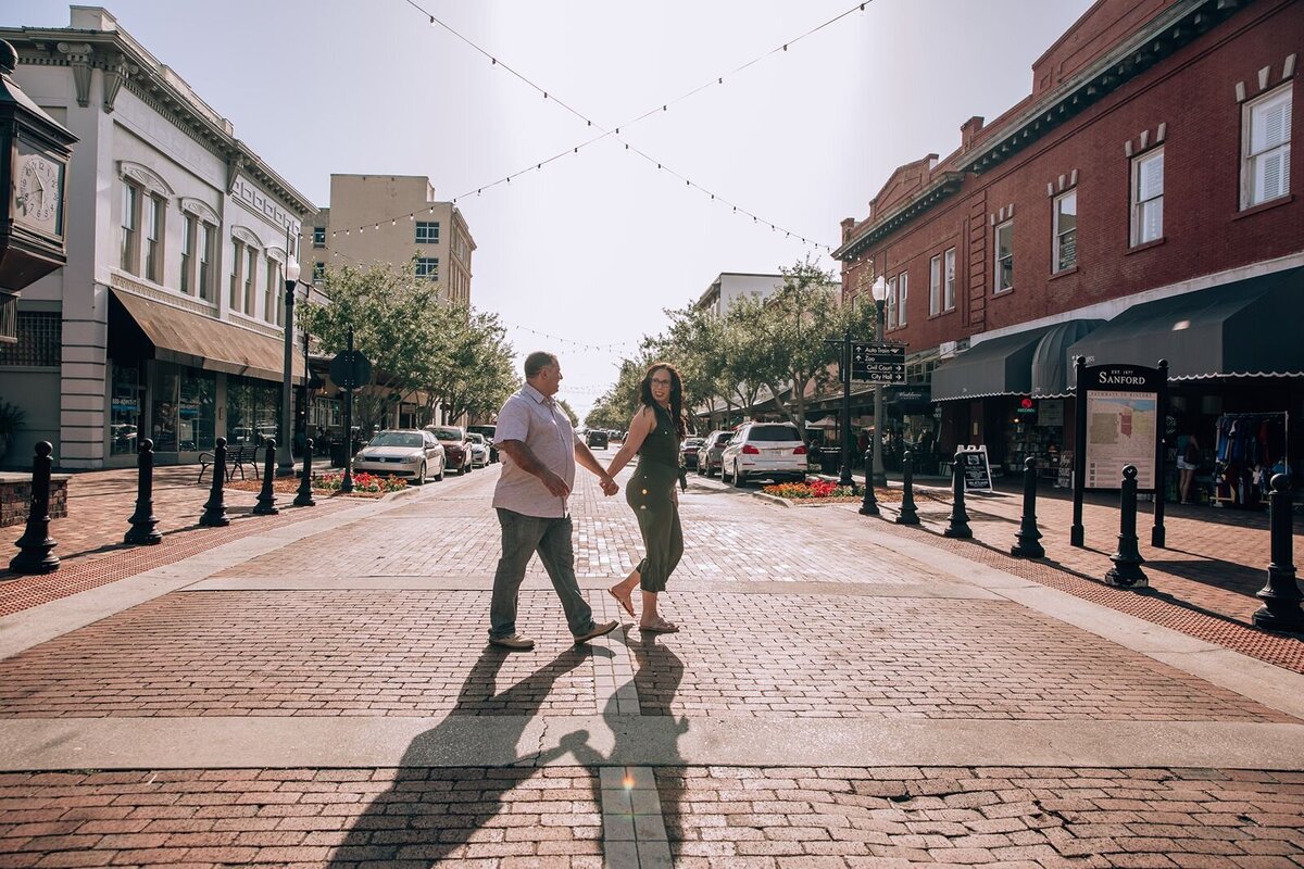 engaged couple crossing 1st street in downtown historic sanford